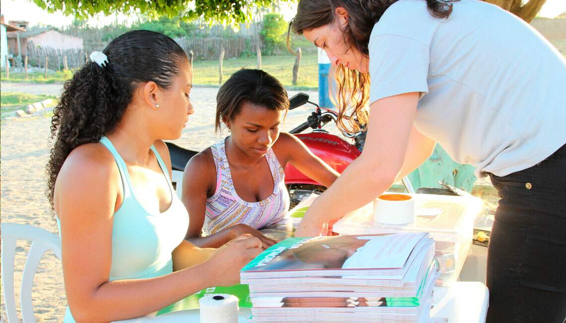 Woman showing a book for two others