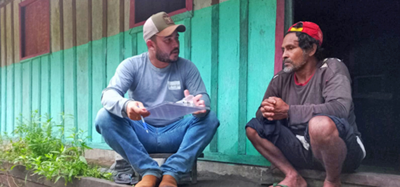 Colaborador da Synergia e produtor de cacau na Amazônia conversam em frente a casa. Foto: Synergia