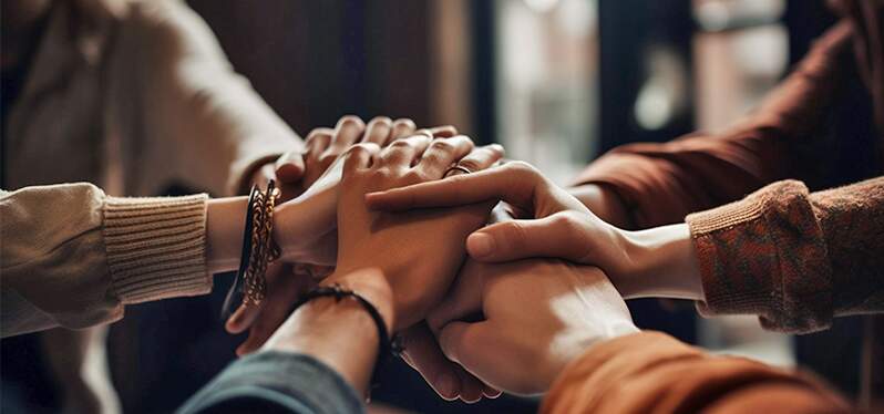 Six people holding hands, community leaders. Photo: Adobe Stock