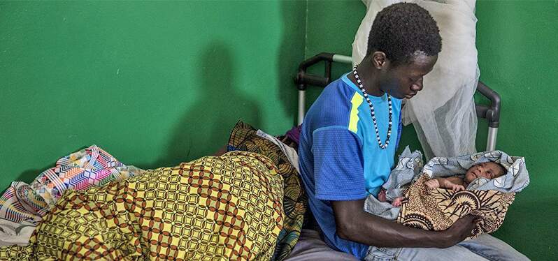 Joven negro con un bebé en el regazo. Líderes comunitarios. Unicef_Zehbrauskas