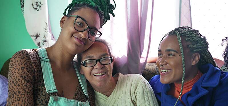 Tres mujeres abrazándose y sonriendo. Foto: Adobe Stock