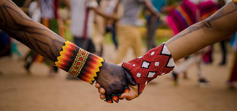 People holding hands with indigenous items. Photo: Adobe Stock