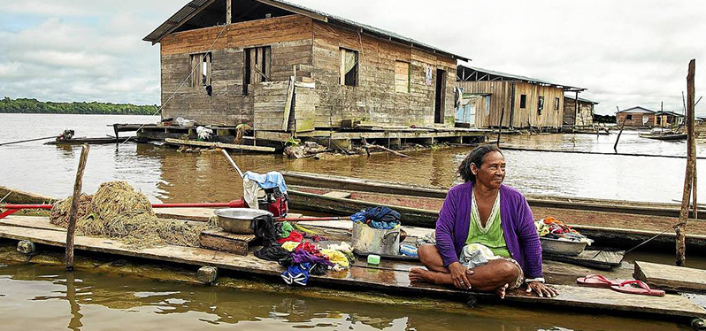 Preservação e valorização dos rios: mulher em casa elevada em rio. Foto: ANTONIO SCORZA