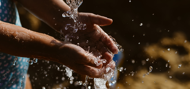 Água caindo sobre as mãos. Água para a paz. Foto: Adobe Stock