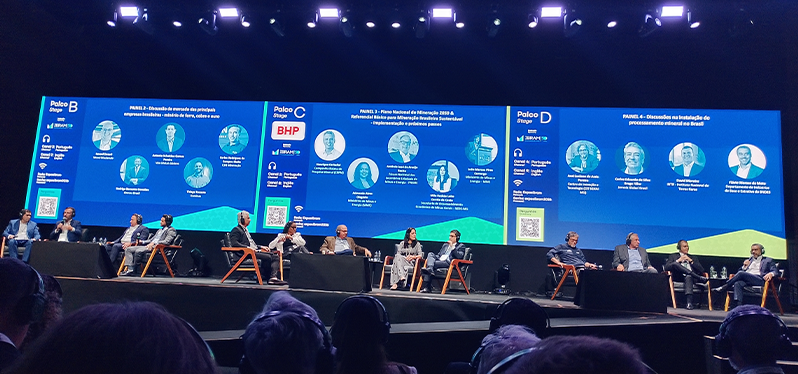 Auditório da Exposibram 2026 durante mesa de debates sobre mineração, com especialistas no palco e grandes telões exibindo painéis sobre inovação, processamento mineral e desenvolvimento sustentável do setor mineral brasileiro.
