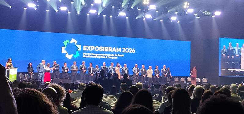 Cerimônia de abertura da Exposibram 2026, um dos principais eventos da mineração no Brasil, com autoridades e representantes do setor reunidos no palco diante de uma ampla plateia. O telão exibe a marca do evento e destaca a relevância da mineração para a economia brasileira.