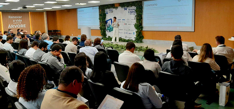 Auditório com profissionais participando de palestra sobre sustentabilidade, papel e inovação em evento.